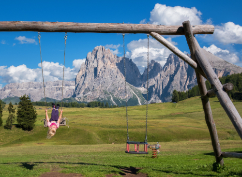 A girl dangerously playing in a swing upside-down which is a sign of bad parenting 